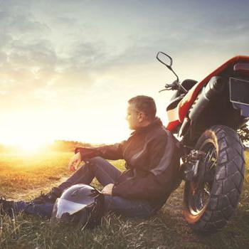 A motorcyclist watches the sun set.